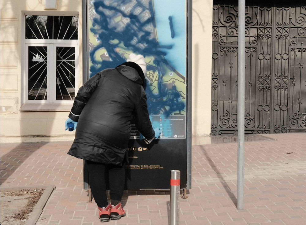A municipal worker uses spray paint to cover over tourist maps in Kyiv. The aim is to make it more difficult for Russian saboteurs to navigate the city.